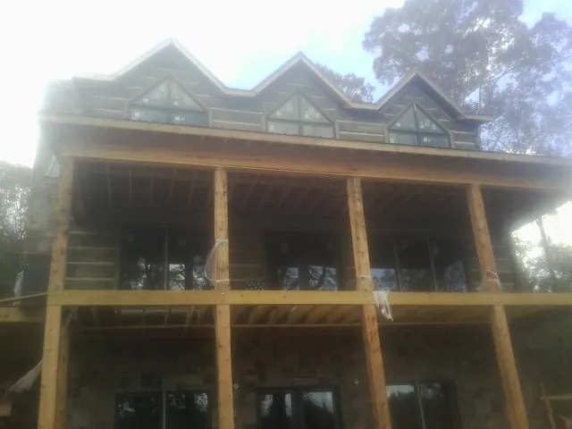 Dormers and porch framing on a large log home under construction — Roof Coating work by our crew in Gordo
