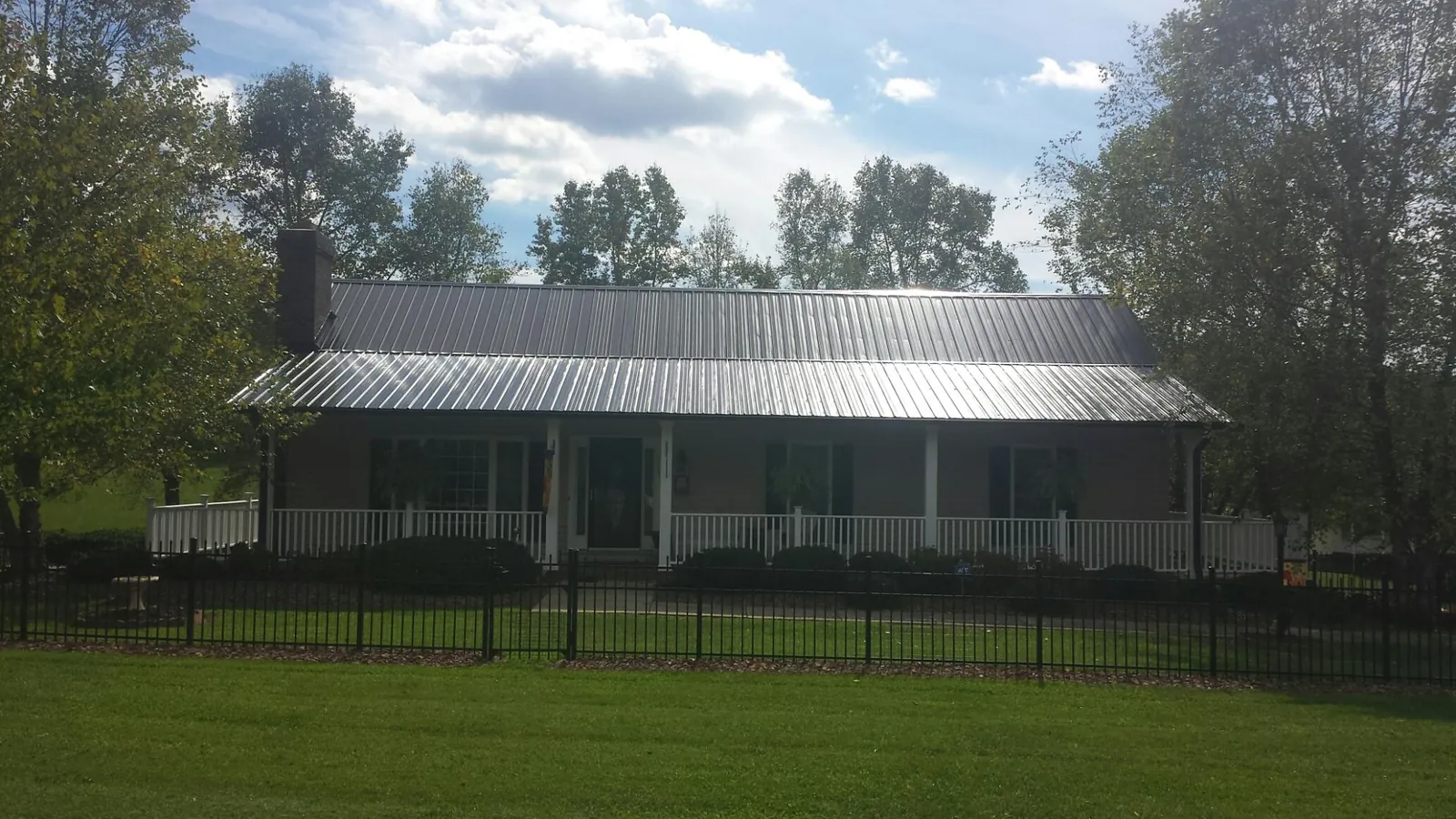 Gray metal roof on a brick ranch with a full width front porch — Gutter Guard Installation work by our crew in Gordo