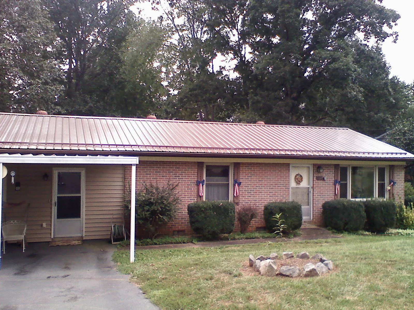 Bronze metal roof and carport on a brick ranch home — Roof Repair work by our crew in Gordo