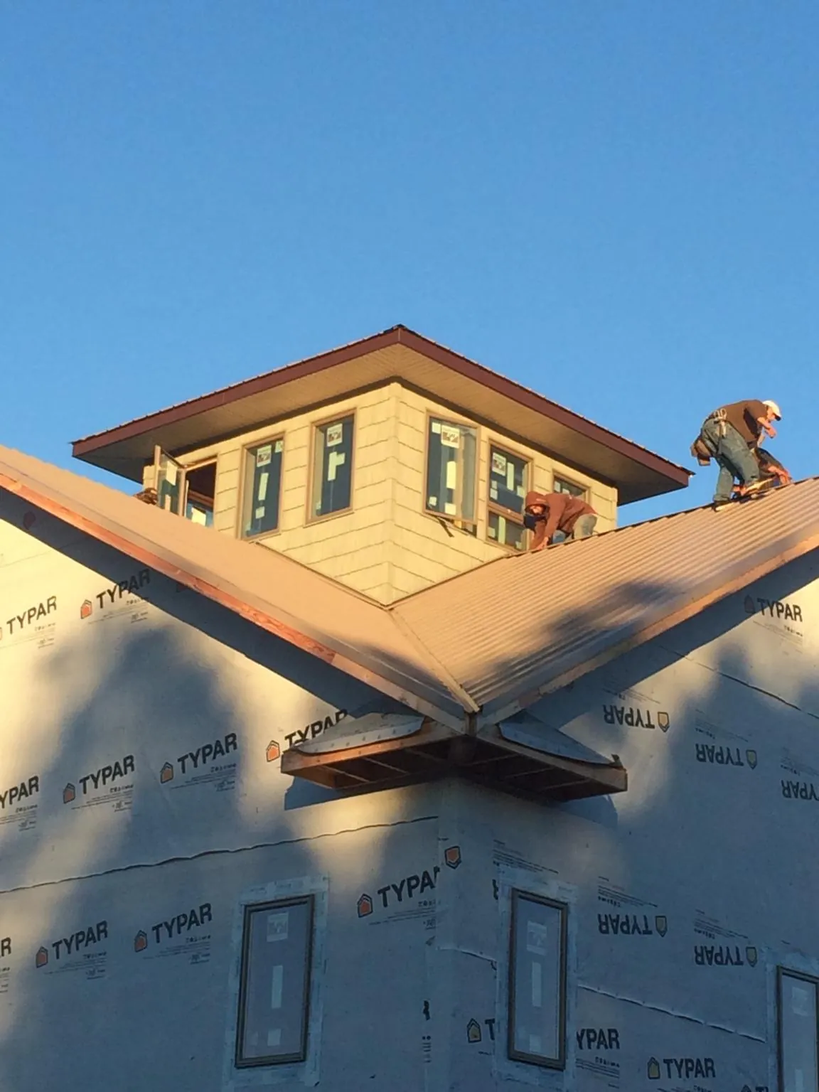 Roofers working around a rooftop cupola on a new metal roof at sunset — Roof Waterproofing in Gordo by Roofing Brothers